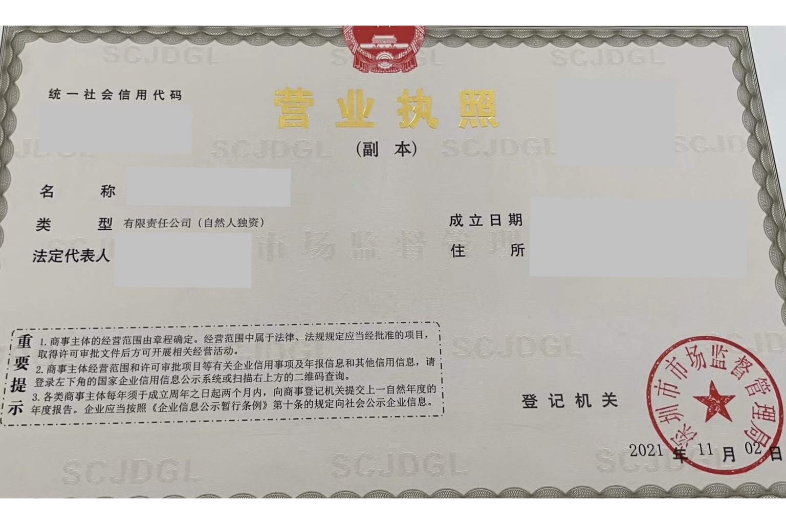 A Chinese business licence photographed on a desk, showing the unified social credit code field, entity type, and a red official seal of the Shenzhen market supervision authority