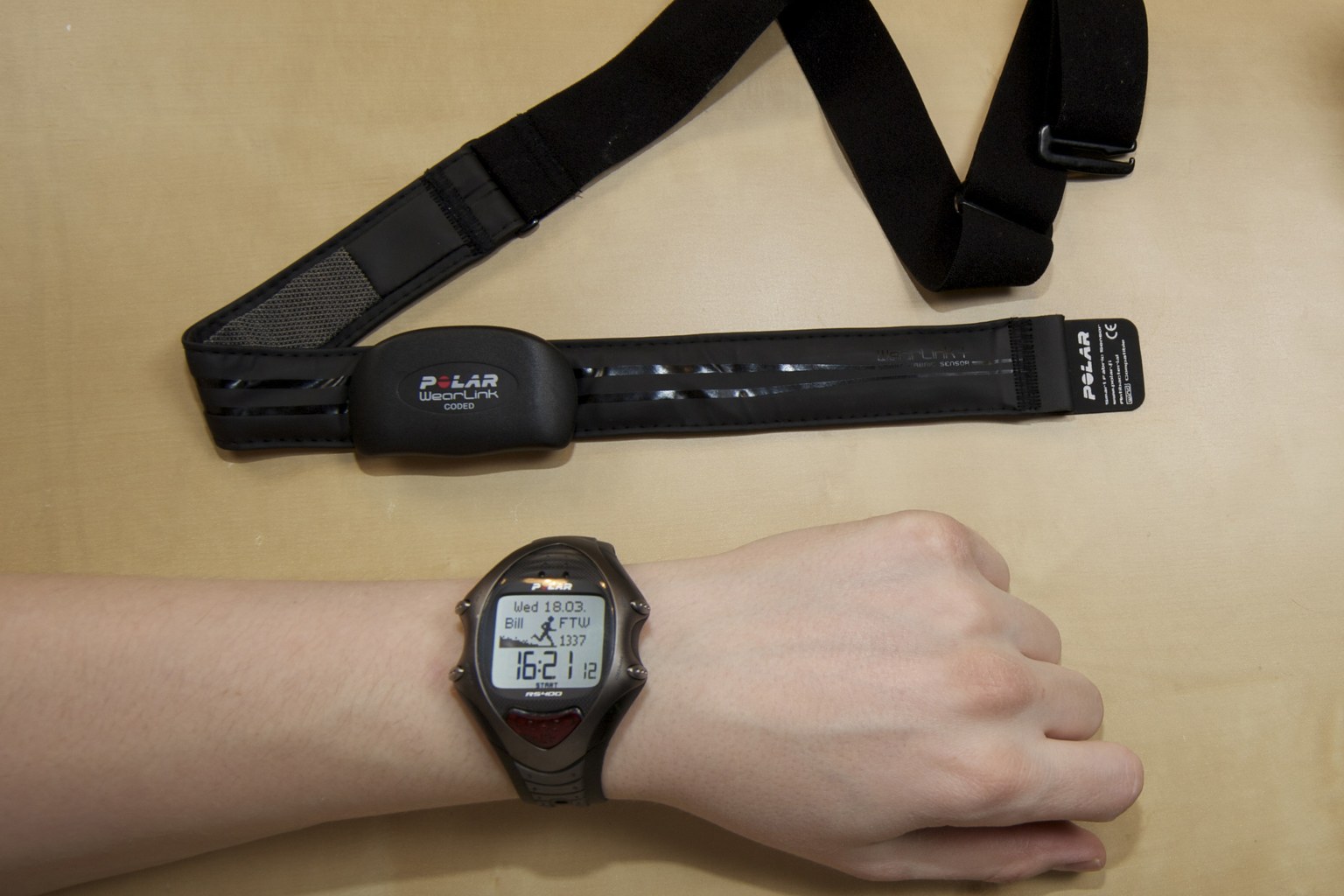 A chest strap heart rate belt with the matching wrist unit resting on a surface, the kind of reference instrument used to validate optical heart rate sensors worn elsewhere on the body