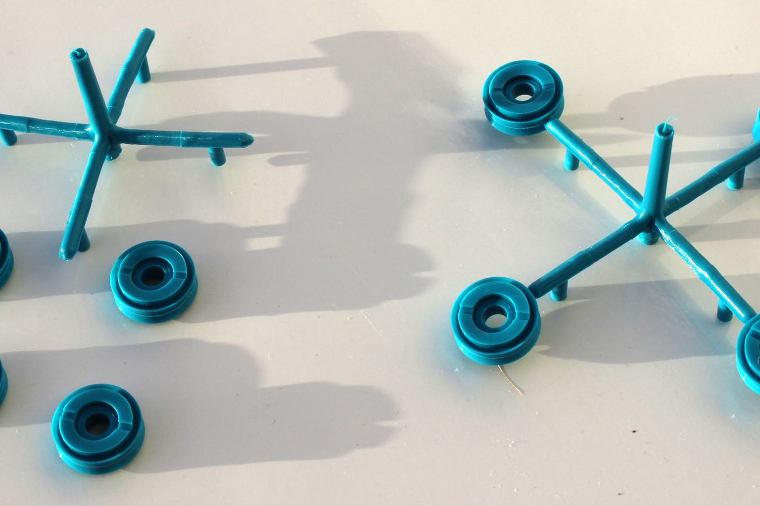 Teal injection-moulded plastic parts lying on a white surface, still attached to their runners and sprue