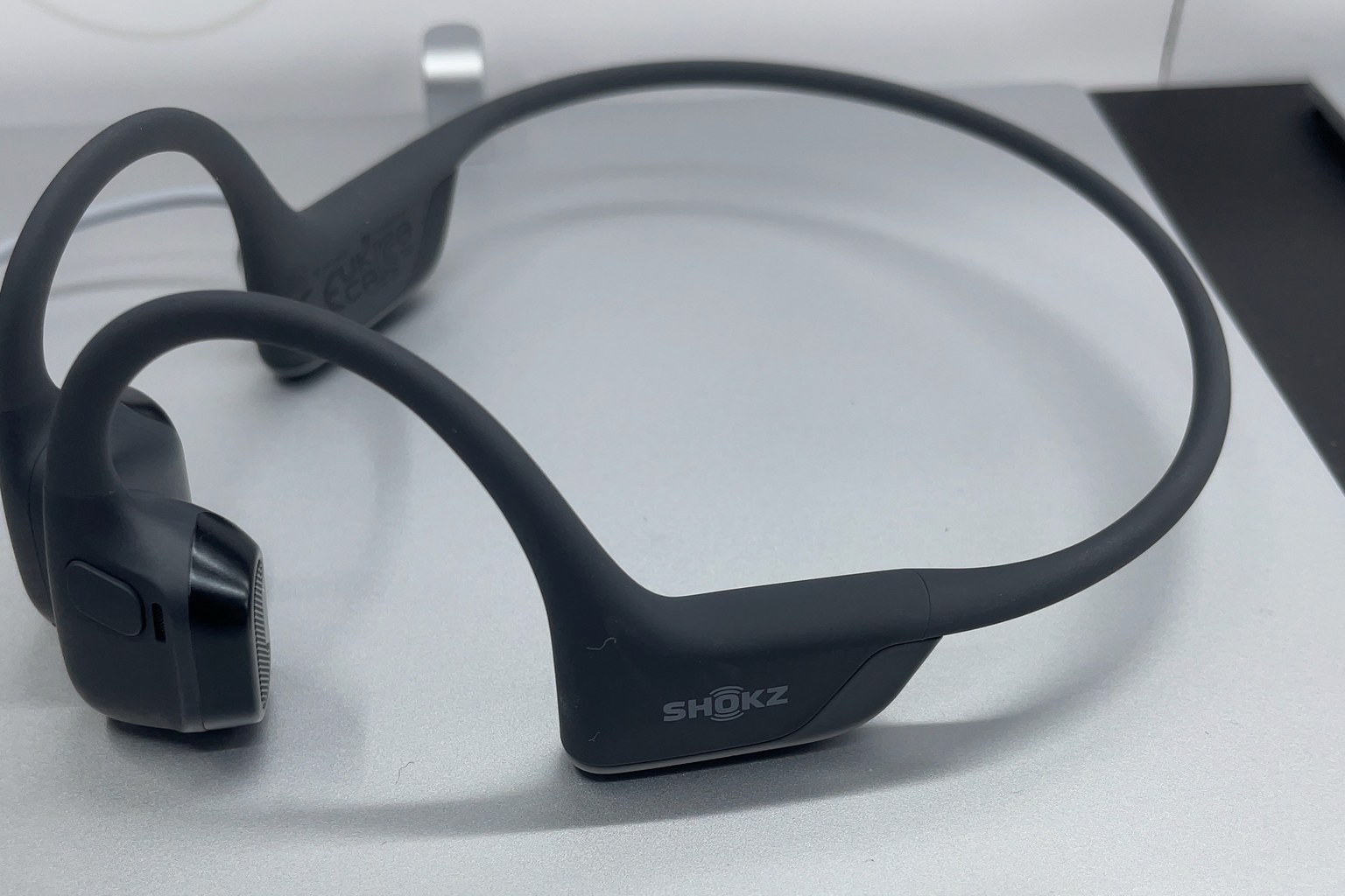 A bone conduction headset with a band that runs behind the head, resting on a display stand