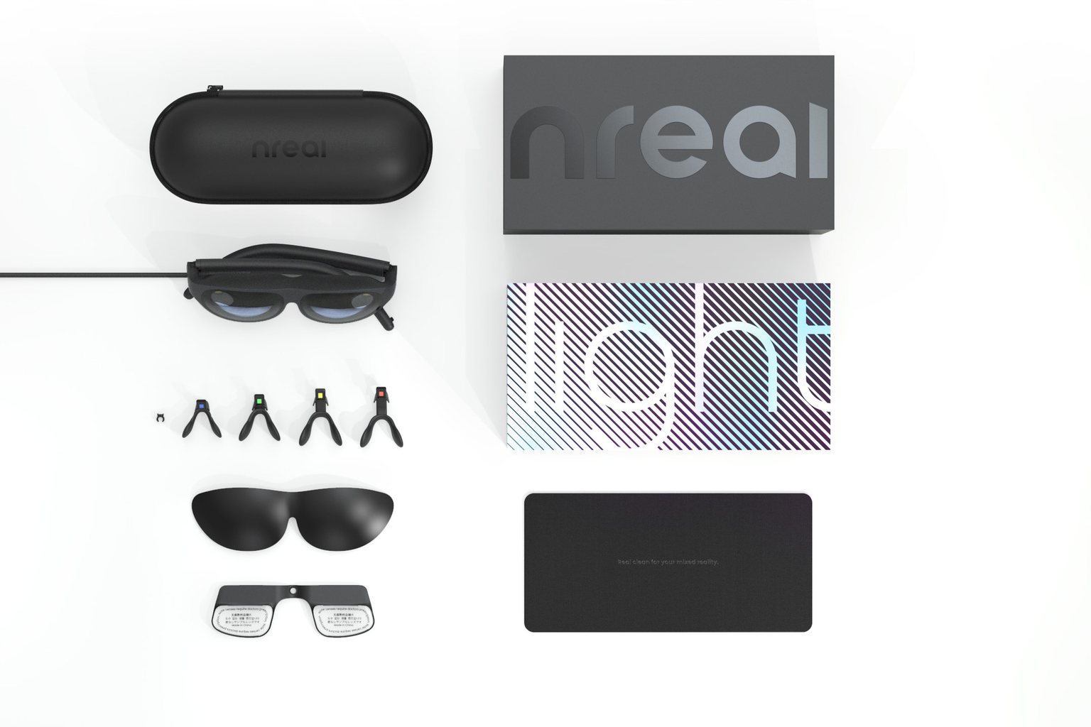 A flat-lay of the Nreal Light consumer kit: black birdbath display glasses, a carry case branded nreal, interchangeable nose pieces, tinted lens covers and prescription inserts